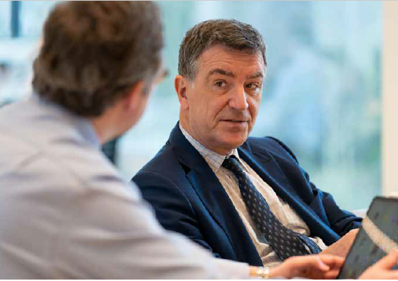 A person in a suit talking to another person

Description automatically generated with low confidence